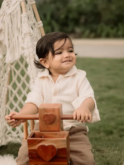A happy toddler enjoys a ride on a wooden tricycle prop during his outdoor adventure shoot.