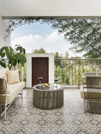 The balcony of the home office, with its patterned tiles and comfortable seating, offers a perfect spot for a break or an informal meeting.
