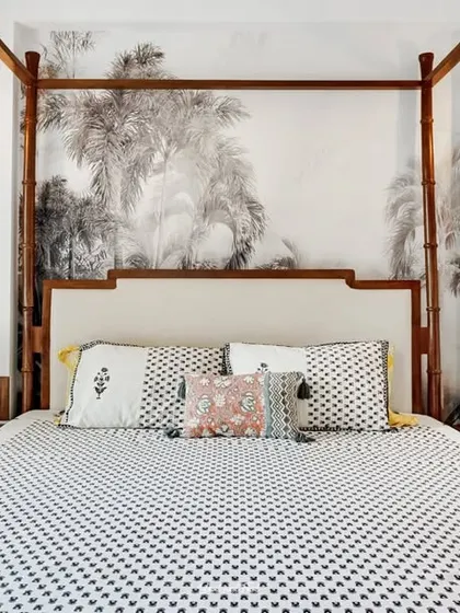 A master bedroom featuring a four-poster bed set against a wall with a subtle, large-scale tropical mural. The design is serene and sophisticated, creating a peaceful retreat.