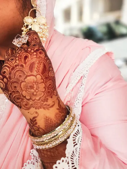 A beautiful floral mandala stain, perfect for an Eid celebration or any festive event. The design is complemented by elegant jewelry and a lovely pink outfit.