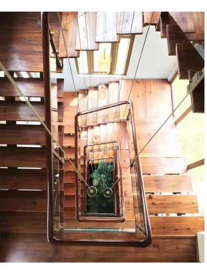 A view looking down the central staircase, which wraps around an open core. This design not only connects the floors but also acts as a light well, drawing sunlight down into the heart of the home. The mix of timber and steel adds a modern touch.