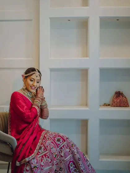 A sweet candid of the bride sitting down, adjusting her jewelry with a happy smile.