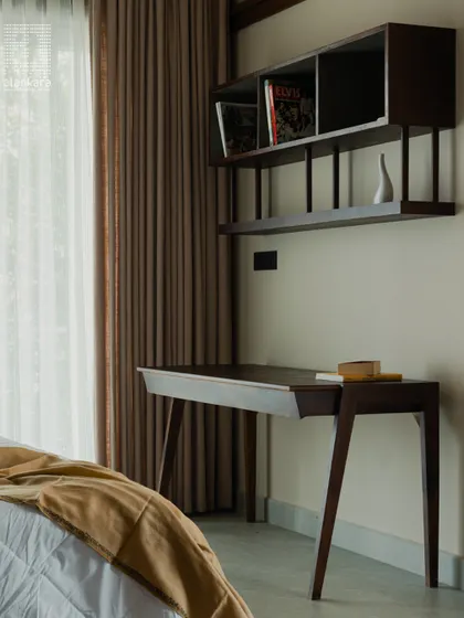 Functionality meets style with this custom-designed study nook within a bedroom. The sleek, wall-mounted bookshelf and minimalist wooden desk create a dedicated workspace without compromising the room's restful ambiance.