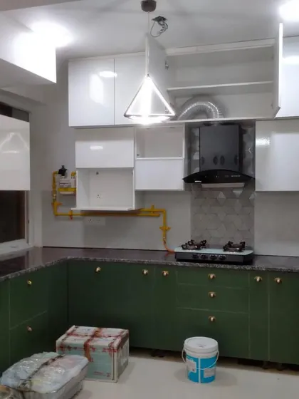 A delivered kitchen project featuring a unique combination of olive green lower cabinets and glossy white upper cabinets. The design is both colorful and practical, with a built-in chimney and ample storage.