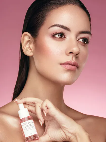 This portrait shows the model holding a bottle of Centella Serum, her pose exuding elegance and confidence. The lighting highlights the contours of her face and the smooth texture of her skin, creating a sophisticated and aspirational image for a skincare campaign.