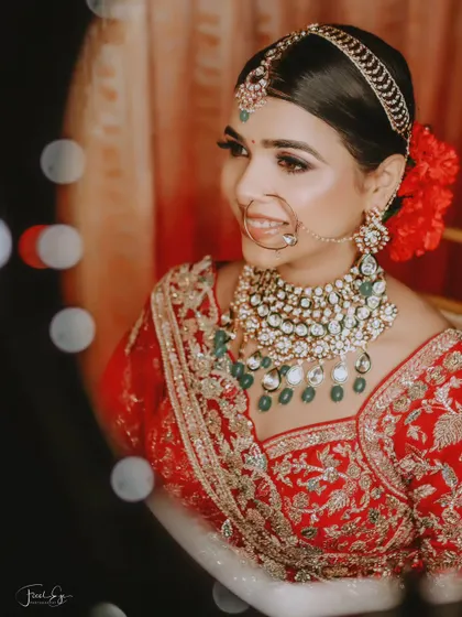 A close-up bridal portrait with beautiful bokeh lights in the background. The focus is on her stunning necklace and happy expression.