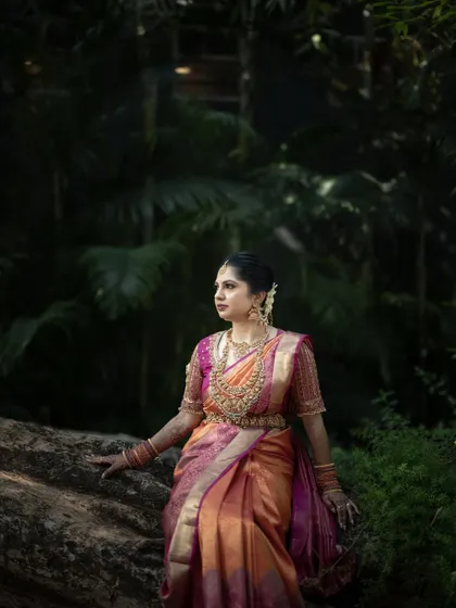 A bride surrounded by the lush greenery of a garden. The soft, natural light beautifully illuminates her traditional attire and serene expression.