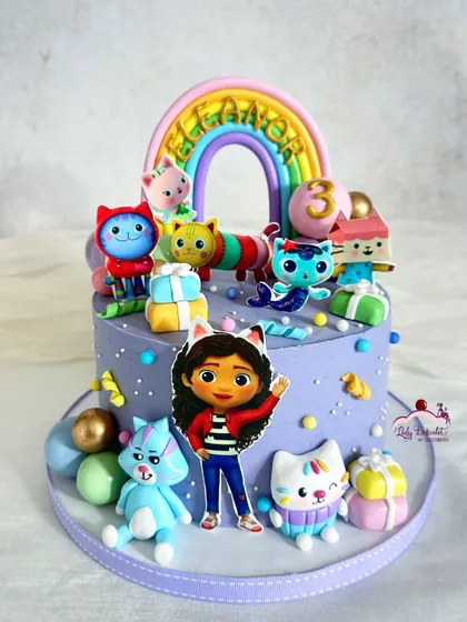 A purr-fectly cute cake for a Gabby's Dollhouse fan! This lavender cake is covered in all of Gabby's cat friends, a rainbow, and lots of colorful details.
