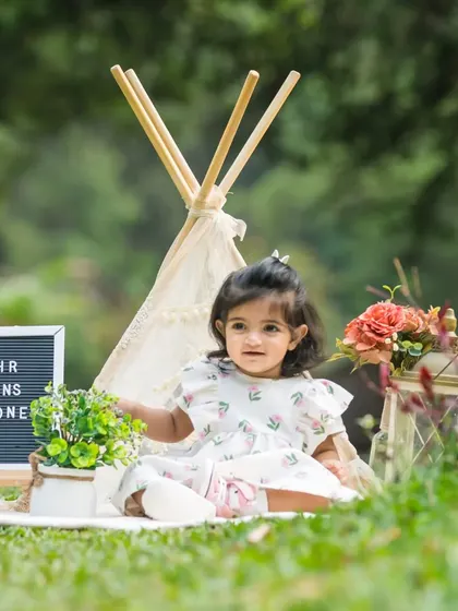One half of a beautiful twin duo, this little girl enjoys her outdoor first birthday shoot with a teepee and sign.