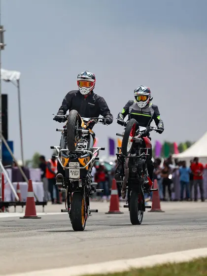 Two stunt riders perform synchronized wheelies, a display of perfect timing and teamwork.