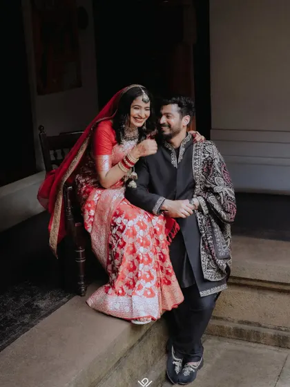 A candid and joyful moment of a couple sharing a laugh on the steps of a traditional house.