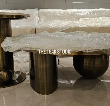 A set of modern, sculptural coffee tables with a metallic finish, shown here wrapped and ready for delivery. The set includes a spherical base table and a cylindrical side table, showcasing our ability to create unique, contemporary designs.