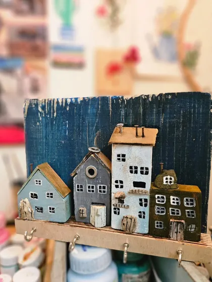 A close-up of a keyholder in progress, showing the detailed miniature houses. This piece combines functionality with our love for creating tiny, charming architectural art.