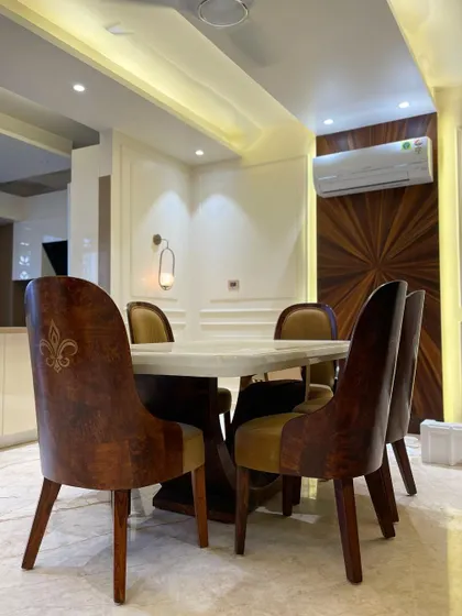 We believe every meal should be an experience. This dining space combines a solid marble table with custom-upholstered chairs and a striking veneer accent wall, creating an atmosphere of warm sophistication.