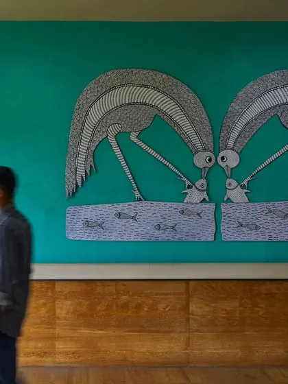 A man walks past a large Gond art mural in the JSW Sanjeevani Hospital. Integrating art from local traditions was key to making the hospital feel less institutional and more like a welcoming community space that celebrates regional culture.