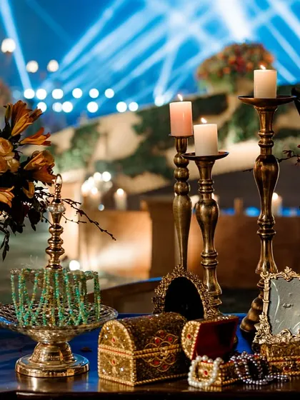 Another view of the elegant table decor, with the blue stage lighting in the background creating a cool, dramatic contrast. The mix of brass, crystal, and florals adds texture and sophistication.