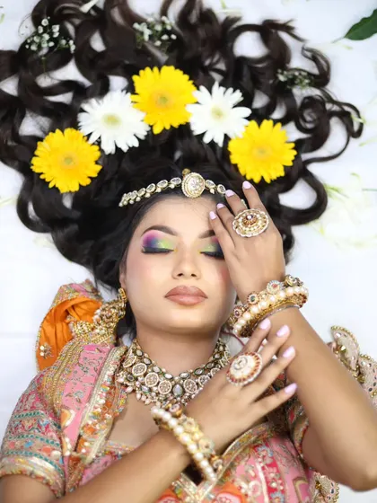 A creative flat-lay pose with flowers in the hair, demonstrating a modern approach to bridal photography and makeup.