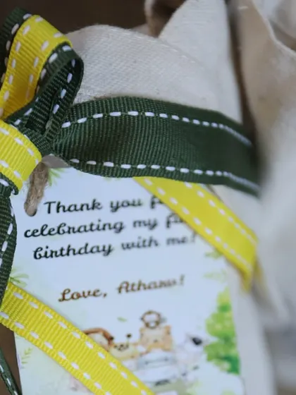 A close-up of the personalized tag on the jungle tote bag, thanking guests for celebrating Atharv's first birthday.