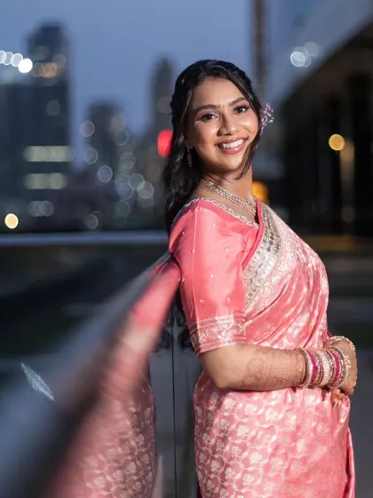 A portrait of the bride at her reception. The city lights in the background create a beautiful bokeh, and her makeup is soft and luminous.