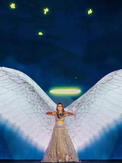 A bride's performance with projected angel wings and a halo against a starry night sky. This is an example of how we use technology to create magical, thematic moments.