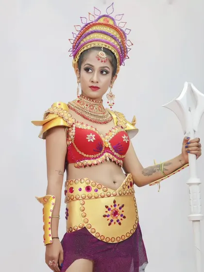 A powerful pose in our custom-designed female warrior costume, complete with golden armor, a red top, and a weapon prop.