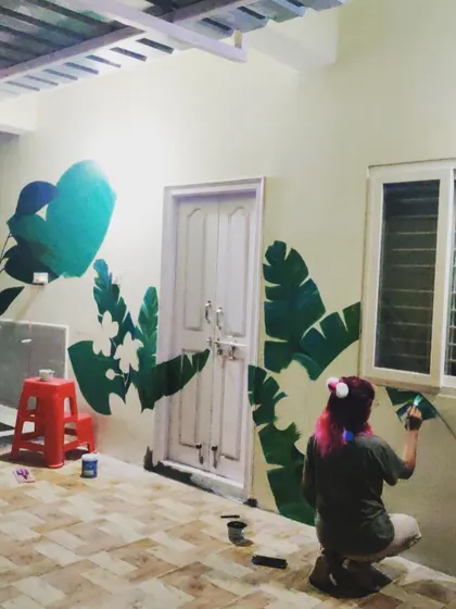 This image captures the early stages of a large botanical mural taking over a balcony wall. I start by mapping out the composition with large leaf shapes, creating a framework around doors and windows before filling in the colors and details.