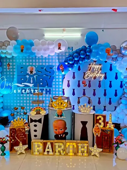 For Parth's 3rd birthday, I designed this Boss Baby setup featuring a circular backdrop with a neon 'Happy Birthday' sign. The theme is carried through with character-themed plinths, a balloon arch, and illuminated marquee letters.