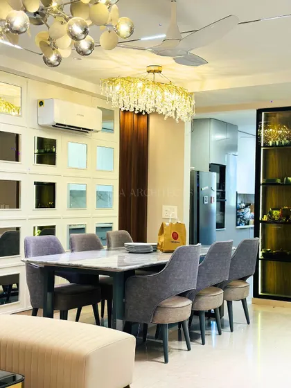 A grand dining area featuring a mirrored accent wall that enhances the sense of space. A crystal chandelier adds a touch of glamour above the marble dining table.
