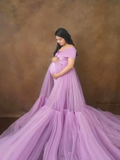 A serene studio portrait in a light lavender gown with an expansive, flowing train. This style creates a soft and dreamy look, perfect for timeless maternity pictures.