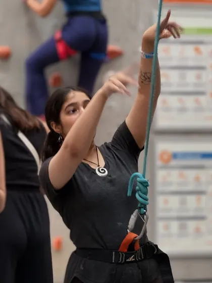 A climber manages the rope for her partner, demonstrating the teamwork and trust that is central to the sport.