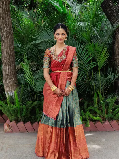 A full-length shot showcasing the beautiful traditional half saree. The makeup and hair complete this timeless South Indian look.