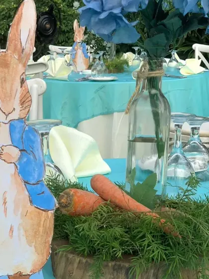 A charming centerpiece detail, featuring a Peter Rabbit cutout, fresh carrots, and greenery on a wooden slice, perfectly capturing the theme.