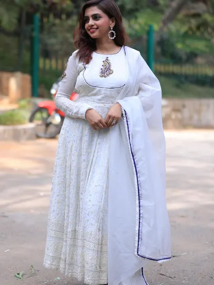 The pure white fabric of the Anarkali is contrasted with a subtle dark blue border on the dupatta, adding a small pop of color to the monochrome look.