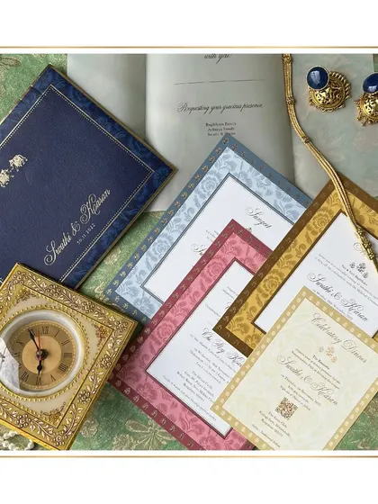 This flat lay showcases the complete royal invitation suite, including the navy blue folder with a gold-foiled elephant motif. The different colored cards for each event create a vibrant and cohesive set.