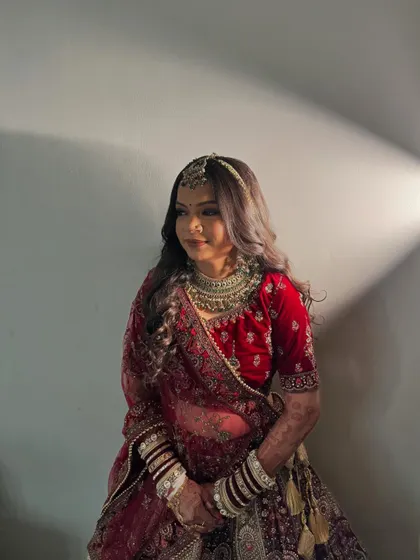 A beautifully lit portrait that captures the rich texture of the velvet lehenga and the soft glow of her bridal makeup.