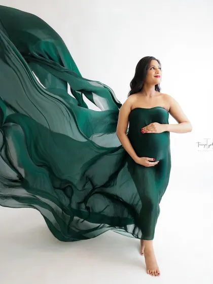 A powerful and graceful portrait. The flowing dark green fabric creates a stunning sense of movement, highlighting the mom-to-be's strength and beauty.