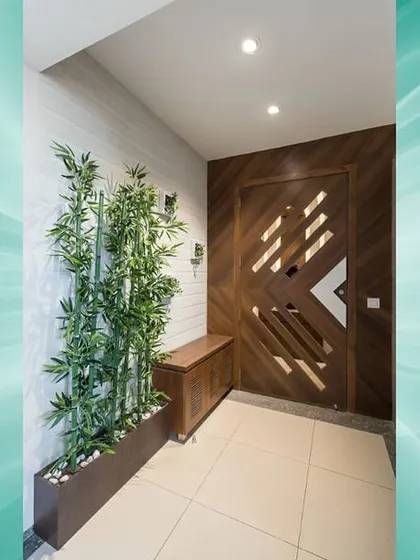 An elegant foyer featuring a door with a unique geometric cutout design. The addition of a bamboo planter brings a touch of nature and tranquility to the entrance.