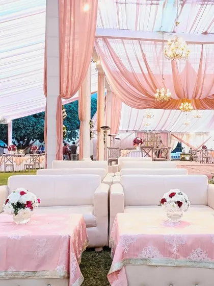 A comfortable and chic lounge area with white sofas and pink tables, part of a pastel-themed wedding in Jim Corbett.