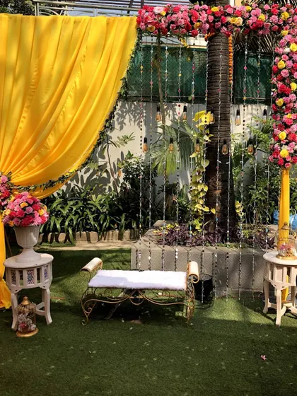 A lovely outdoor photo booth for a Haldi ceremony. The setup includes elegant seating against a backdrop of yellow drapes and floral arrangements, perfect for capturing memories.