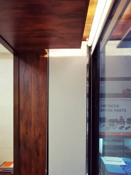 A detail shot showing the junction of different materials: wood paneling, glass partitions, and a clean white wall, illustrating our focus on precise execution.