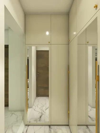 A minimalist wardrobe design with glossy off-white doors and sleek golden handles. The mirrored panels help create a sense of spaciousness in the walkway.