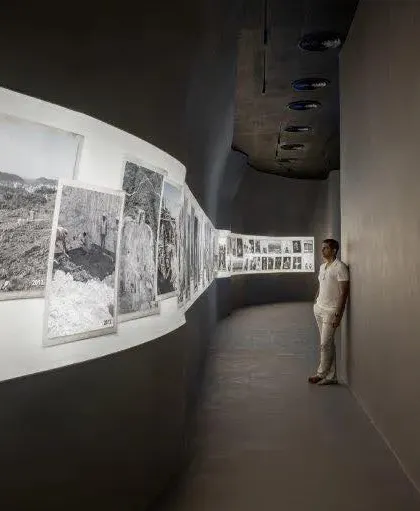 The Aatma Manthan Museum by Sanjay Puri Architects, shortlisted for WAF Interiors. This image shows a visitor in a curved gallery space, where black and white photographs document a historical narrative.