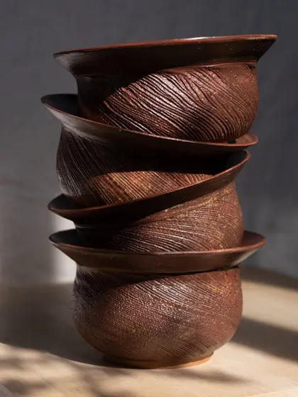 A stack of planters from 'The Dhora' Collection. The carved textures are reminiscent of shifting sands, creating a sense of movement and stillness.