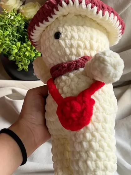 A close-up of the mushroom toy's friendly face and little red bag.
