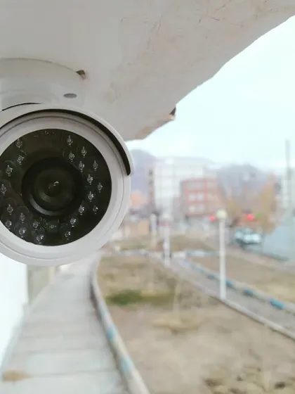 This dome camera is positioned to monitor a wide area, such as a parking lot or public space. Its discreet design and durable housing make it suitable for outdoor surveillance.