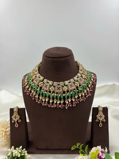 The Divya Premium Antique Gold Necklace set. This piece features unique square motifs with Meenakari work, layered with green and ruby beads for a colorful yet traditional look.