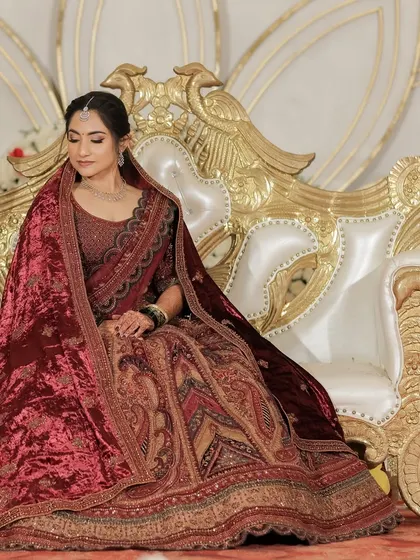 Ujwala's royal reception look in a magnificent maroon velvet lehenga. The makeup is classic and timeless, fitting for a palace wedding.