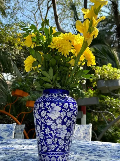 A beautiful blue and white patterned vase with yellow flowers, used as a centerpiece on a table with a matching block-printed cloth.