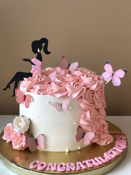 A "Queen" cake with a cascade of pink buttercream roses and a stylish silhouette topper.