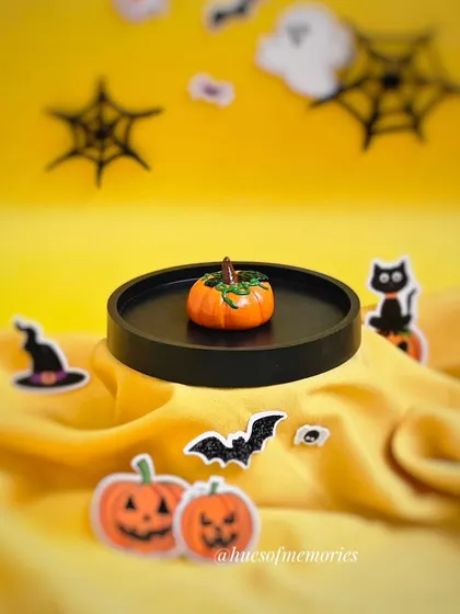 A wider shot of the pumpkin trinket tray, set against a festive yellow background with Halloween-themed cutouts.